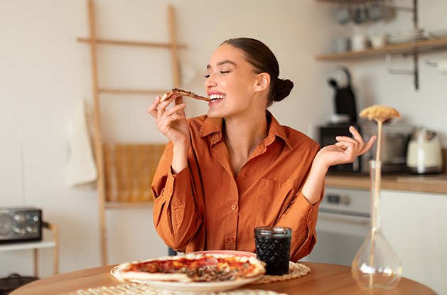 Woman enjoying slice of pizza at home