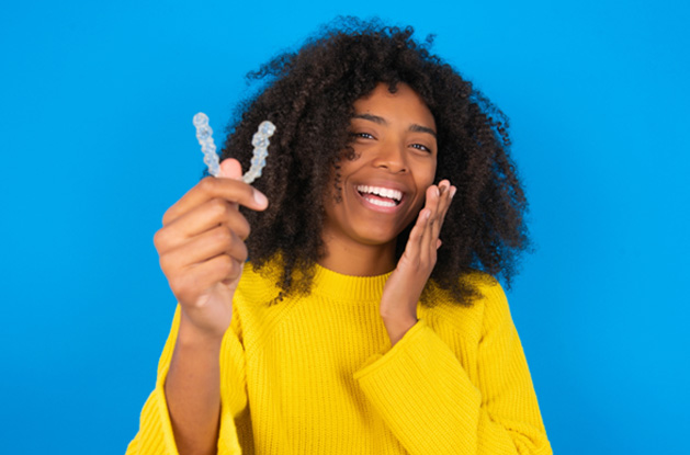 a patient smiling after removing her Invisalign aligner