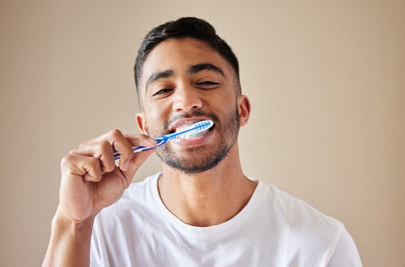 Man in white t-shirt brushing his teeth