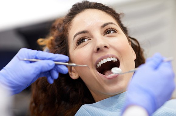 Woman with curly brown hair undergoing dental exam