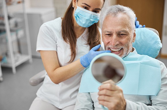 Dentist showing man with white hair his teeth in a mirror