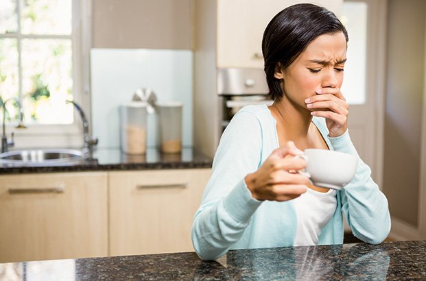 Woman experiencing dental sensitivity from hot cup of coffee